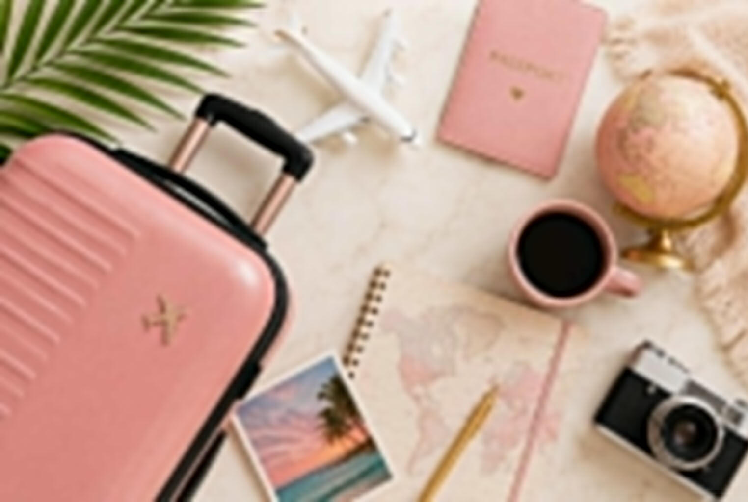 Planificación de viajes a medida Portodoelmapa Elementos de viaje sobre escritorio: valija, pasaporte, avión, cuaderno y accesorios de planificación.
